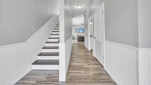 A hallway with a wooden staircase, white walls, and a ceiling fan. - The Blue Escape- 5BR/2.5BA, Huge Private Pool and Hot Tub. Steps to the Beach (Panama City)