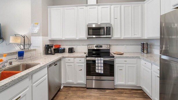 A modern kitchen with white cabinets, stainless steel appliances, and a granite countertop. - Beautiful 2 Bedroom Home Near Old Town Spring (Humble)