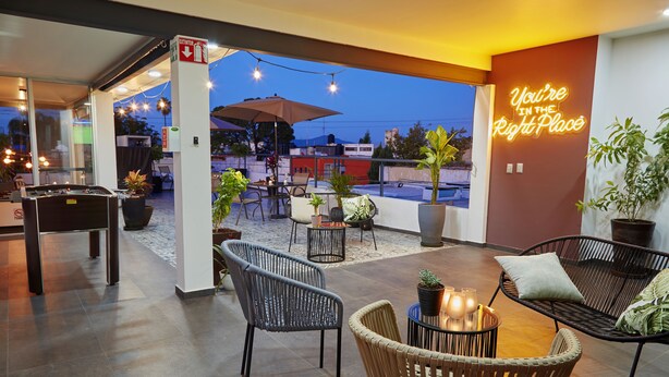 An outdoor seating area with wicker chairs, a pool table, and potted plants. - Casa Cheljo (Guadalajara)
