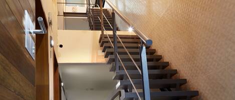 Un escalier moderne avec une rampe en métal, menant à l’étage supérieur.