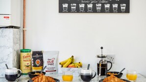 Una mesa de desayuno con café y pastelería, un cartel del menú de café y una cafetera.