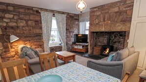 Ein gemütliches Wohnzimmer mit Steinwand, Kamin, Fernseher und bequemen Sitzgelegenheiten.