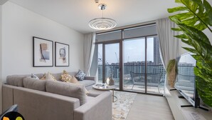 A modern living room with a grey sofa, a coffee table, and a large window offering a city view. - Palace Waterfront Living Dubai Creek  (Dubai)