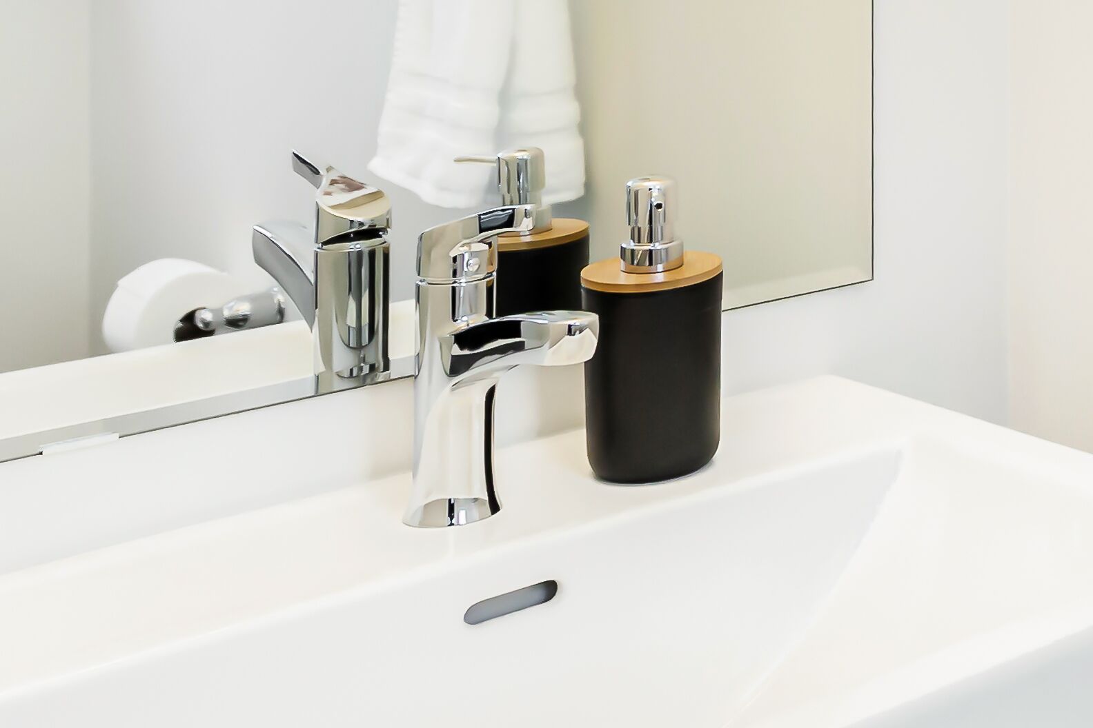 Une salle de bain moderne avec un robinet chromé, un distributeur de savon noir et un lavabo blanc.