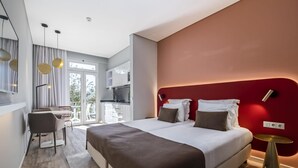 A modern hotel room with a large bed, a desk, and a dining area. - King David Suites 201 by Homie (Funchal)