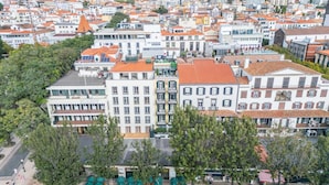 A high-rise hotel with multiple floors, a central courtyard with seating, and a view of the surrounding cityscape. - King David Suites 201 by Homie (Funchal)