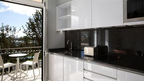 A modern kitchen with white cabinets, a black countertop, and a view of the outdoors. - King David Suites 201 by Homie (Funchal)