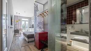 Ein modernes Schlafzimmer mit einem Bett, einer roten Kommode, einem Schreibtisch und einer Glastrennwand.