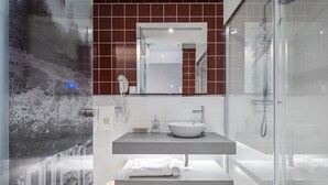 A modern bathroom with a large mirror, a white sink, and a glass shower enclosure. - King David Suites 501 by Homie (Funchal)