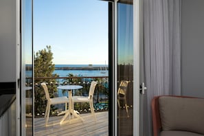 Un balcon avec une table et des chaises, une vue sur la mer et un bâtiment visible au loin.