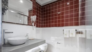 Ein modernes Badezimmer mit einem weißen Waschbecken, einem Spiegel, einem Handtuchhalter und einer roten Fliesenwand.