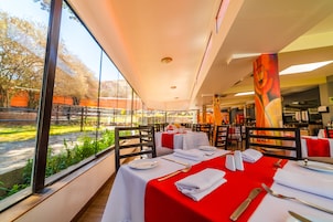 Un restaurante con mesas dispuestas para comer, amplios ventanales y vistas al exterior.