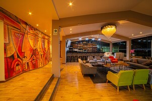 Un vestíbulo amplio con una zona de bar moderna, asientos cómodos y un vibrante mural abstracto en la pared.