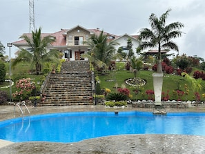 Una casa con piscina, escalones de piedra y jardines tropicales.