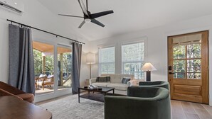 A modern living room with a sofa, armchairs, a coffee table, and a ceiling fan. - The River Nest-Hot Tub & River View (Fountain Lake)