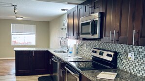 Una cocina moderna con gabinetes de madera oscura, electrodomésticos de acero inoxidable y un salpicadero de azulejos.