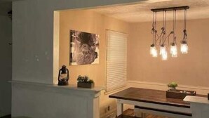 A modern kitchen with a wooden dining table, pendant lights, and a small island with a lantern. - Three Kings Ranch (Indianapolis)