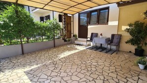 A patio with stone flooring, two chairs, a table, and potted plants. - SUNNY Studio Apartment (Rovinj)