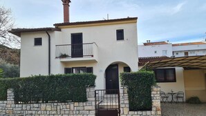 A two-story building with a stone wall, a black gate, and a small patio area with chairs. - SUNNY Studio Apartment (Rovinj)