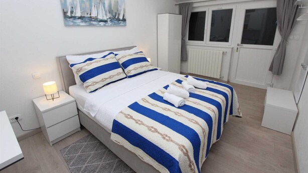A neatly arranged bedroom with a bed, nightstands, a painting, and a window with curtains. - SUNNY Studio Apartment (Rovinj)