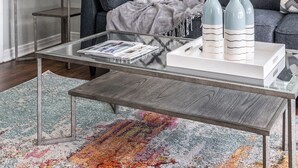 A modern living room with a gray sofa, a glass coffee table, and a colorful rug. - Urban Cowboy  (Fort Worth)