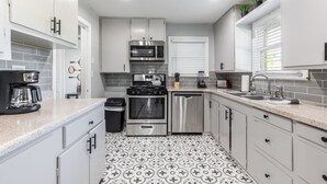 A modern kitchen with white cabinets, a stainless steel stove, and a dishwasher. - Urban Cowboy  (Fort Worth)