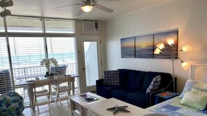 A room with a bed, a desk, a chair, a ceiling fan, and a window with a view of the ocean. - Ocean Front Studio on Boardwalk (Virginia Beach)