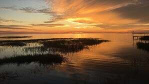 A sunset over a calm water body with a dock extending into the water. - Gulf front RV Site, full hook up .take a breath and enjoy the sunsets (Perry)