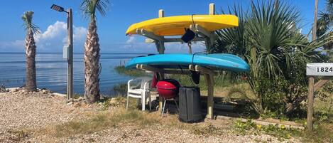 A beachside setting with a wooden structure holding kayaks and a sign with the number 1824.