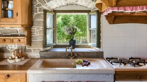 A rustic kitchen with a stone arch window, wooden cabinets, and a gas stove. - Villa Bolara (Istria - Grožnjan) (Grožnjan)