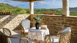 A stone patio with wicker furniture and a lace tablecloth, overlooking a lush green landscape. - Villa Bolara (Istria - Grožnjan) (Grožnjan)