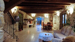 A rustic stone interior with a fireplace, stone walls, wooden beams, a dining area, and a sofa. - Villa Bolara (Istria - Grožnjan) (Grožnjan)