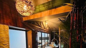Un intérieur moderne agrémenté d’un chemin en pierre, de meubles en osier et d’un luminaire suspendu.