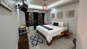 A modern bedroom with a bed, bedside tables, a TV, and artwork on the walls. - Cabin Featuring Jacuzzi and Pool in La Fortuna (La Fortuna)