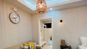 A modern living room with a sofa, a coffee table, a bed, and a ceiling light fixture. - Cabin Featuring Jacuzzi and Pool in La Fortuna (La Fortuna)