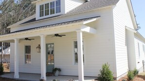 A white two-story house with a covered porch, a small front yard, and a single-story extension.