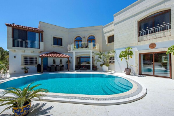 Relax by the pool surrounded by lush greenery and comfortable outdoor seating.