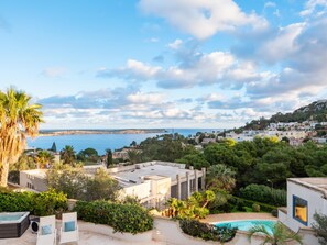 Relax in a pool surrounded by lush greenery and take in the stunning ocean view.