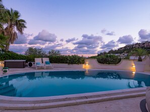 Relax by the serene pool surrounded by a patio area with lounge chairs and a seating space.