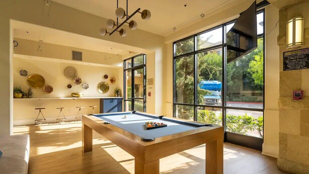 A pool table in a room with large windows, a ceiling light fixture, and a fire safety sign. - Luxury Resort Condo by Six Flags Magic Mountain

 (Santa Clarita)