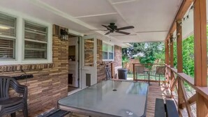 Un patio abrité avec une table à plateau de verre, des bancs et un ventilateur de plafond.