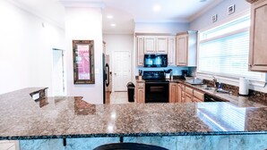 A modern kitchen with granite countertops, wooden cabinets, and a black stove.