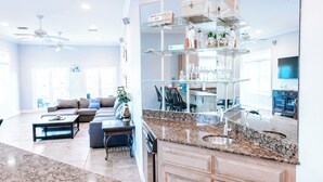 A spacious living area with a kitchen and dining area, featuring a granite countertop, wooden cabinets, and a large mirror.