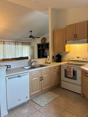 A compact kitchen with a dishwasher, stove, and a ceiling fan.