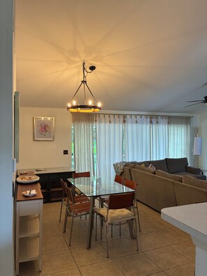 En moderne stue med et glasbord, en sofa og en loftventilator.