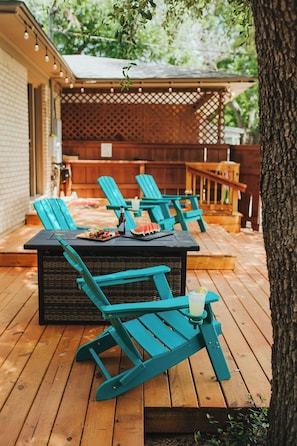 An outdoor patio with a table and chairs, a watermelon slice, and a drink on the table.