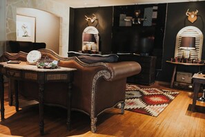 A room with a leather sofa, a wooden table with a basket, and a patterned rug.