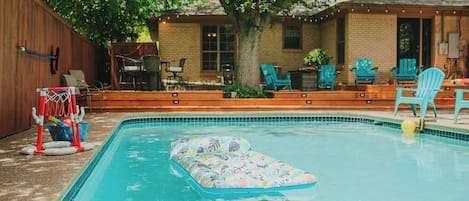 Ein Garten mit Schwimmbad, einer schwimmenden Liege und Gartenmöbeln.
