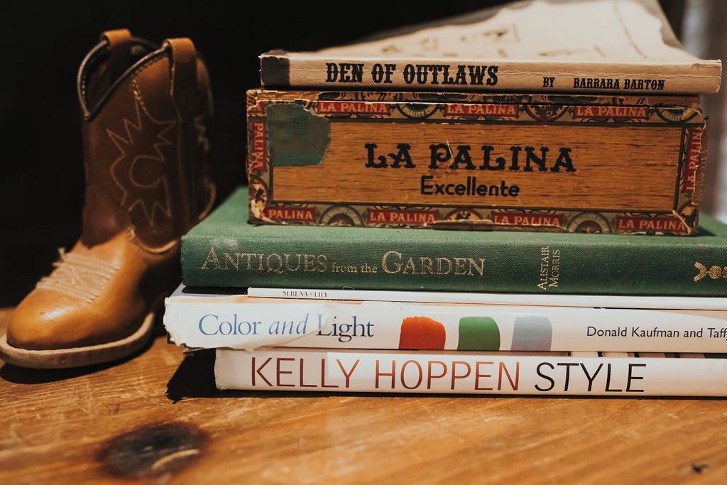 Una pila de libros con títulos como 'La Palina' y 'Kelly Hoppen Style' sobre una superficie de madera.