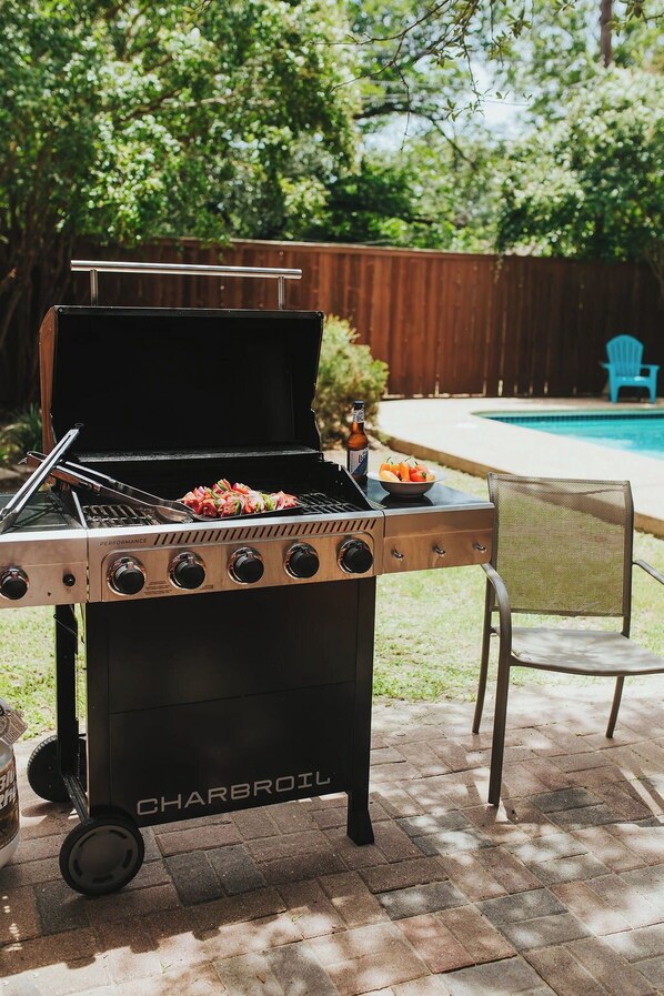 A Charbroil grill with a pool in the background. - Historic Sayles Ranch- Huge Deck + Pool! (Abilene)